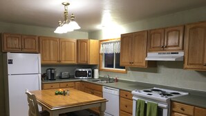A kitchen with wooden cabinets, a white refrigerator, a microwave, a stove, and a sink. - Sage House- in town with LOTS of space (Ennis)