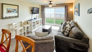 Un salon avec un canapé, des fauteuils, un téléviseur et un balcon offrant une vue agréable.