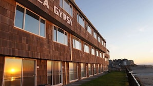 Un immeuble à plusieurs étages, doté de grandes fenêtres, et sur la façade duquel on peut lire l'inscription « SEA GYPSY ».