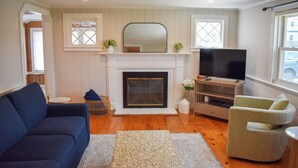A living room with a fireplace, a television, a sofa, and a chair.