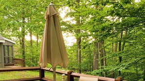Eine Holzterrasse mit Tisch und Stühlen, umgeben von einem Holzgeländer und üppigem Grün.