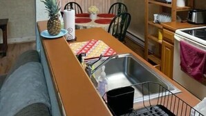 Eine kompakte Küche mit Holzarbeitsplatte, einer eingebauten Spüle und einem Essbereich mit Tisch und Stühlen.