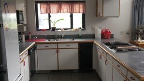 A compact kitchen with white cabinets, a microwave, a sink, and a stove. - Ocean View Matunuck Home - Go to Water, Go to the Village! (Wakefield)