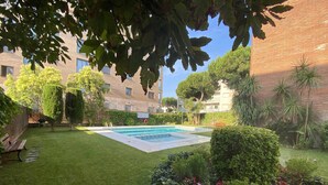 Un jardín bien cuidado con piscina, rodeado de setos podados y diversas plantas.