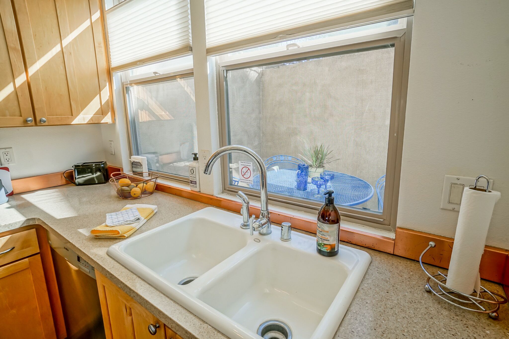 A kitchen with two sinks, wooden cabinets, a window with a view, and a countertop with various items.