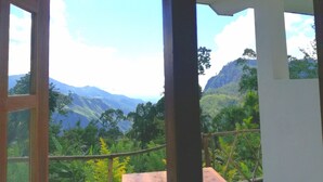 Una habitación con un ventanal grande que ofrece vistas a montañas verdes y un cielo despejado.