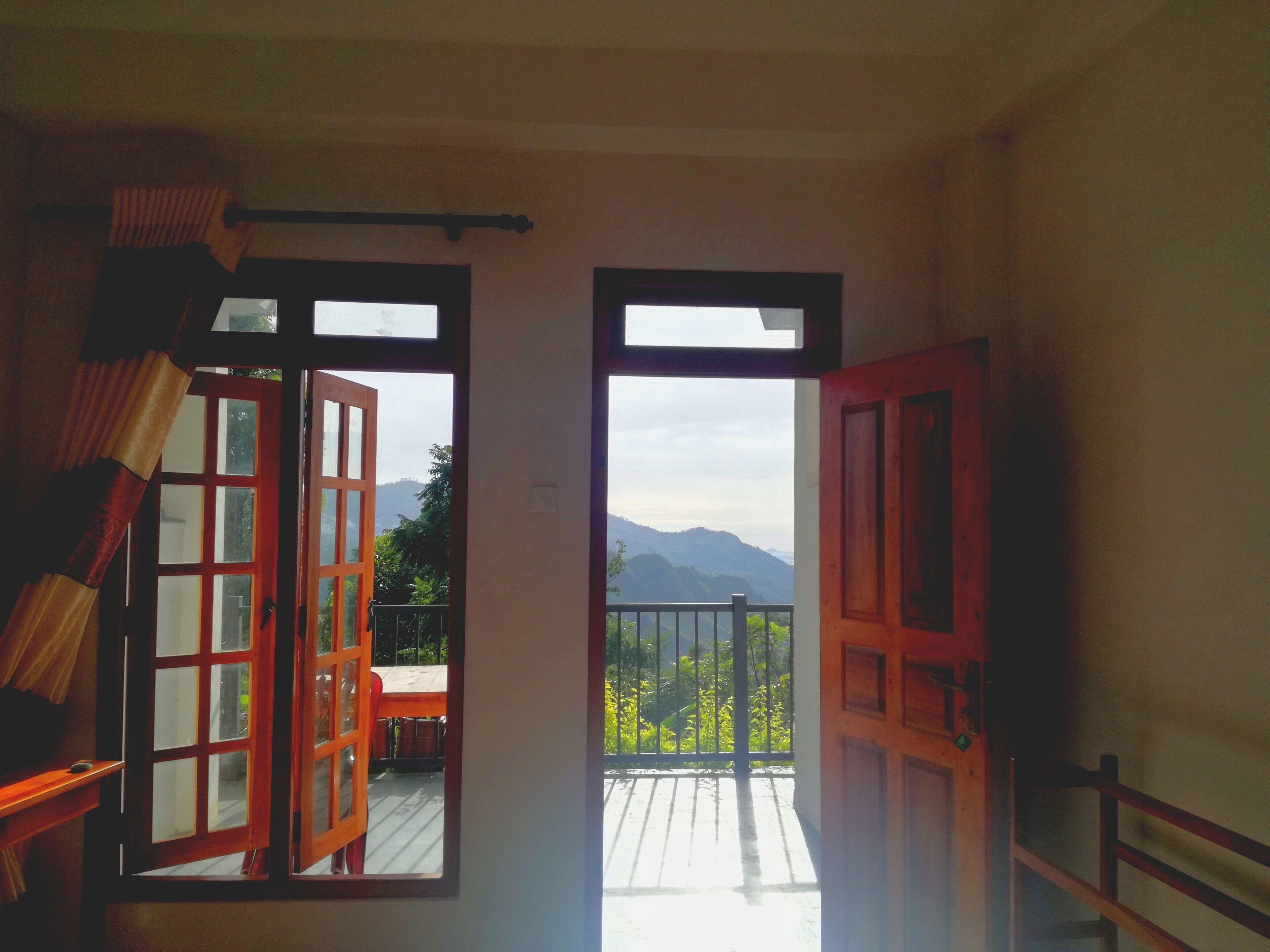Una puerta abierta que da a un balcón con vistas a montañas.