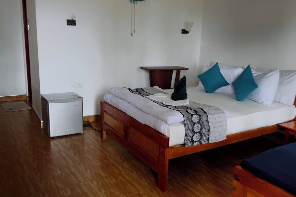Un dormitorio con cama de madera, una mesita de noche, un escritorio pequeño y un cubo de basura.