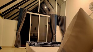 Un dormitorio con cama, ventana con cortinas y tragaluz.