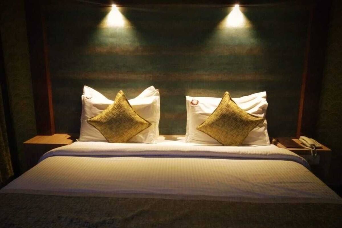 A hotel room with a bed, two nightstands, and two wall-mounted lights.