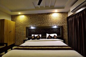 A hotel room with a large bed, a wooden wardrobe, a patterned wall, and an air conditioning unit. - Hotel Mayas (Tiruchirappalli)