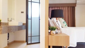 A modern hotel room with a marble bathroom, a bed with a black lamp, and a view through a glass door. - Hotel Matana (Chiang Mai)