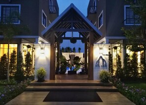 A hotel entrance with a covered walkway, potted plants, and a well-lit facade. - Hotel Matana (Chiang Mai)