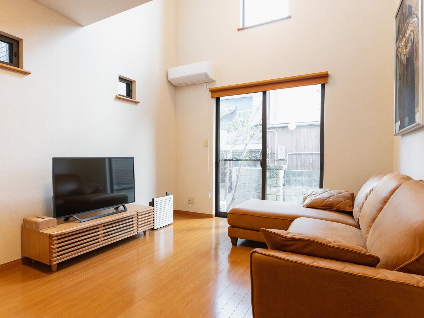 A living room with a TV, a sofa, and a sliding glass door to a backyard.