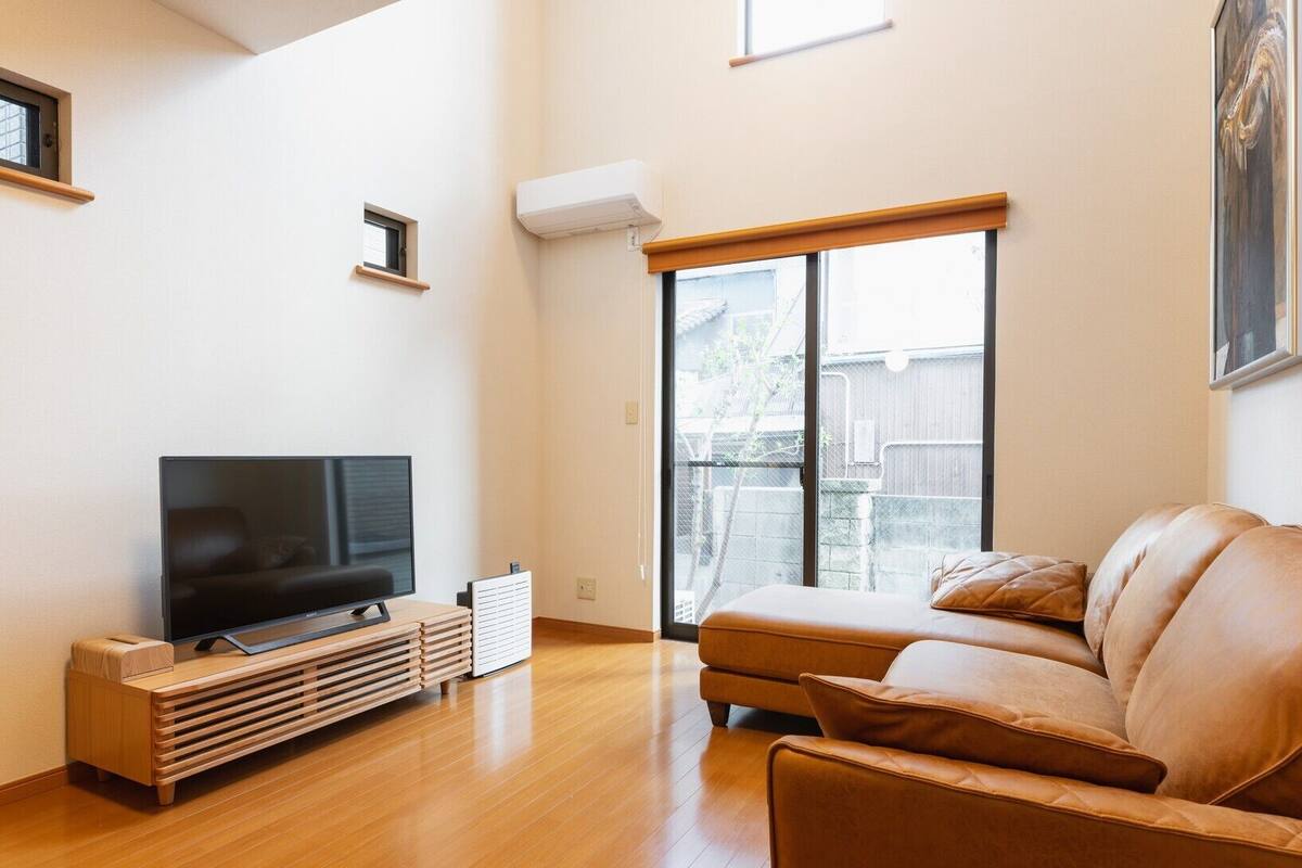 Una sala de estar con televisor, sofá y puerta corrediza al patio trasero.