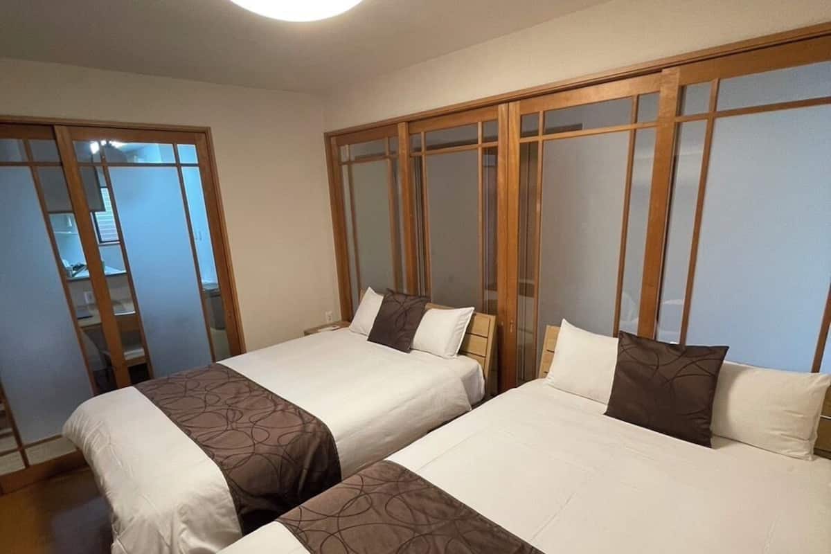 Habitación de hotel con dos camas, un armario corredero e iluminación en el techo.