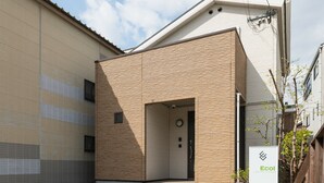 Un edificio con fachada de ladrillo y un gran portón de garaje. Se observa un letrero con el texto 