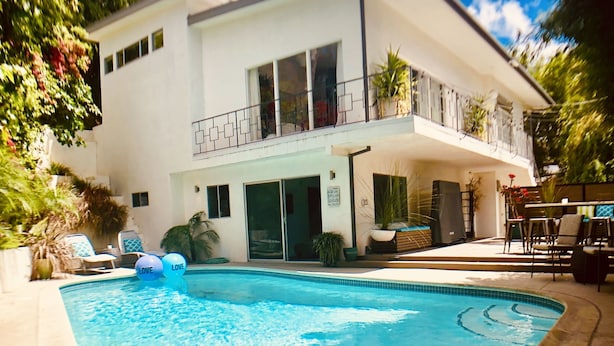 Une maison moderne à deux étages, dotée d’une piscine, de mobilier d’extérieur et d’un balcon.