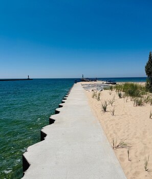 A concrete pier extending into the water with a sandy beach on the right.