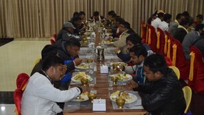 Una larga mesa con personas sentadas en sillas, disfrutando de una comida.