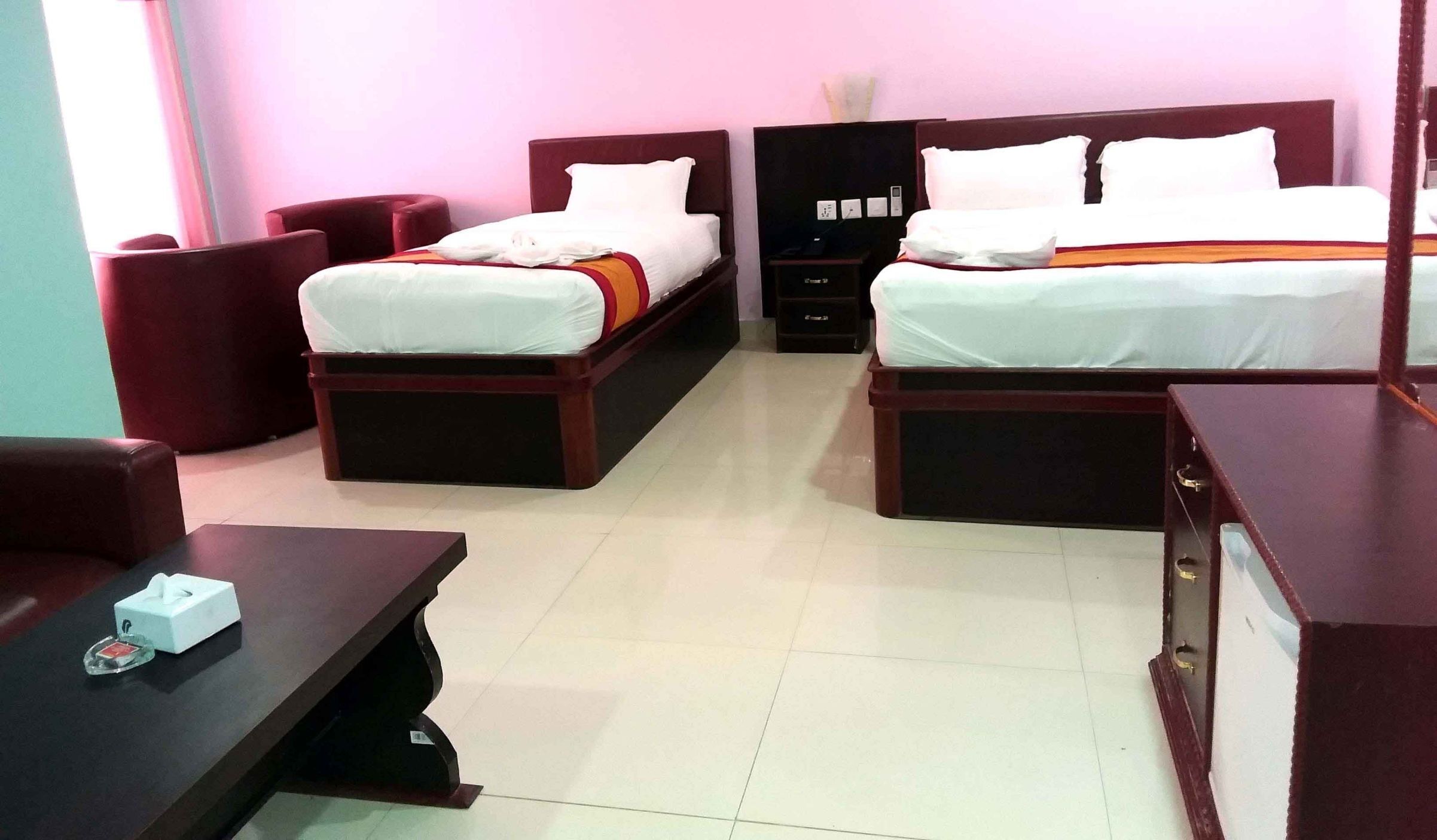 A hotel room with two beds, a desk, a chair, and a nightstand.