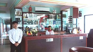 Una zona de bar con mostrador, estanterías llenas de botellas y una caja registradora.