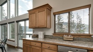 A modern kitchen with wooden cabinets, a Bosch dishwasher, and a window with blinds. - Waterfront house in Bayview! Boating, fishing, amazing views, 12mi to Silverwood (Bayview)