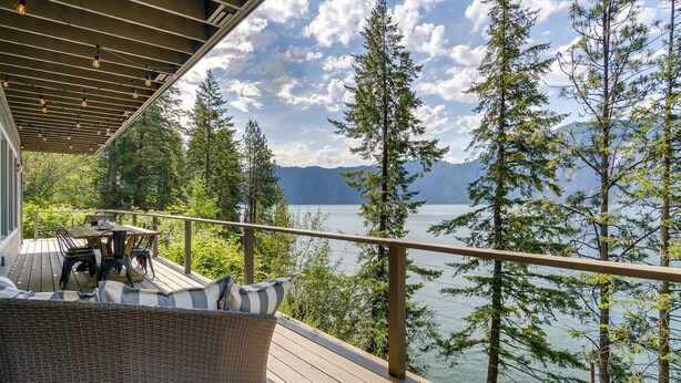 A deck with outdoor furniture, overlooking a lake with trees and mountains in the background. - Waterfront house in Bayview! Boating, fishing, amazing views, 12mi to Silverwood (Bayview)