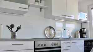 A modern kitchen with white cabinets, a stainless steel oven, a microwave, and a coffee maker. - legendary germany (Bad Harzburg)
