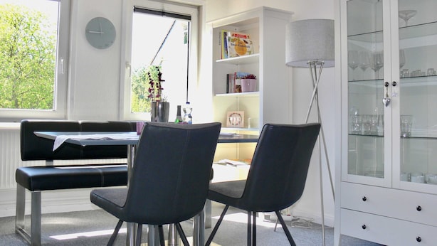 A dining area with a table, two chairs, a bench, a bookshelf, and a cabinet with glass doors. - legendary germany (Bad Harzburg)