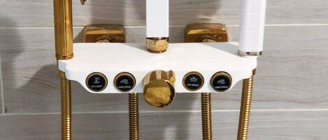 A shower unit with a gold faucet, a white control panel, and a gold showerhead.