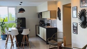 Un saló modern amb zona de menjador, cuina i vistes a vegetació a l'exterior.