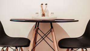Una mesa con dos sillas negras, un mantel blanco y un adorno pequeño sobre la mesa.