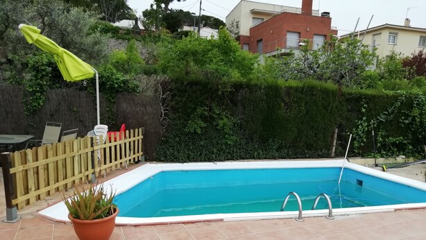 A rectangular swimming pool with a tiled deck, a wooden fence, and a potted plant. - Chalet with mountain views and private pool, ideal for families.  (viladecavalls)