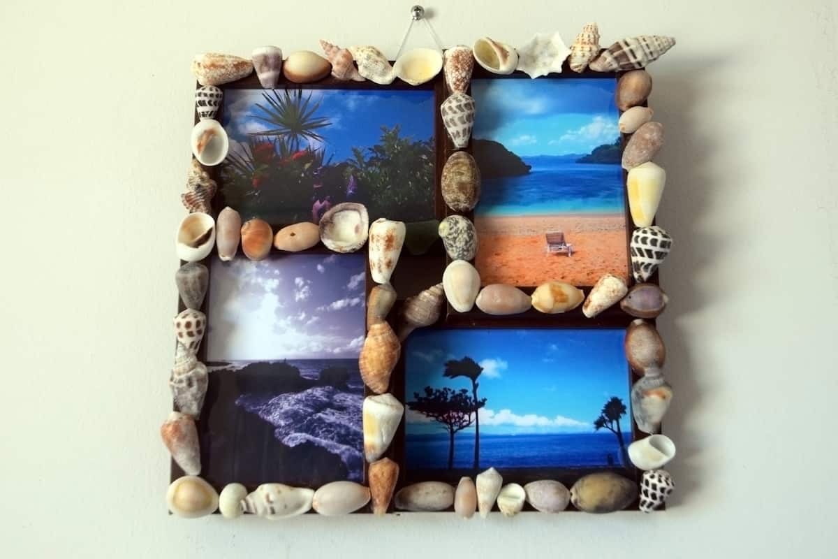 A wall art piece with a beach scene framed by seashells.