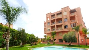 A multi-story building with a swimming pool in the foreground. - Residence Genegelis 4055 (Marrakech)