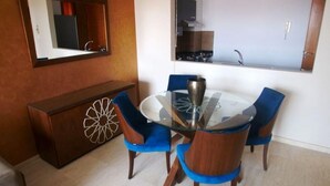 A dining area with a glass table, blue upholstered chairs, a wooden cabinet with a decorative panel, and a mirror on the wall. - Residence Genegelis 4055 (Marrakech)