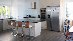 Una cocina moderna con una isla central, electrodomésticos de acero inoxidable y taburetes de bar.