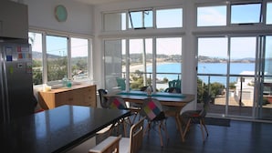 Una cocina moderna con amplios ventanales, una zona de comedor con sillas y vista al mar.