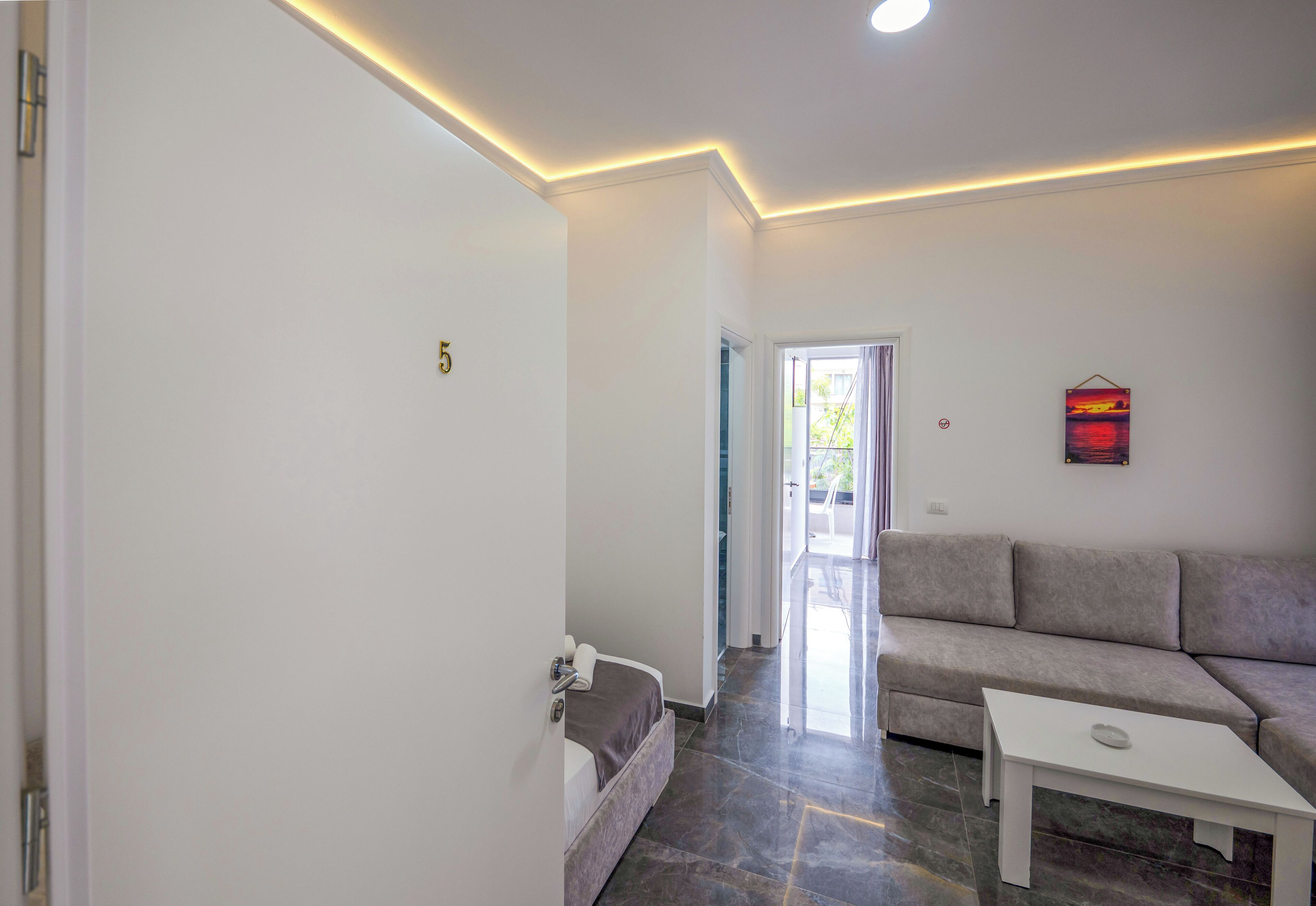 Una sala de estar moderna con un sofá, una mesa de centro y una puerta que da a un balcón.