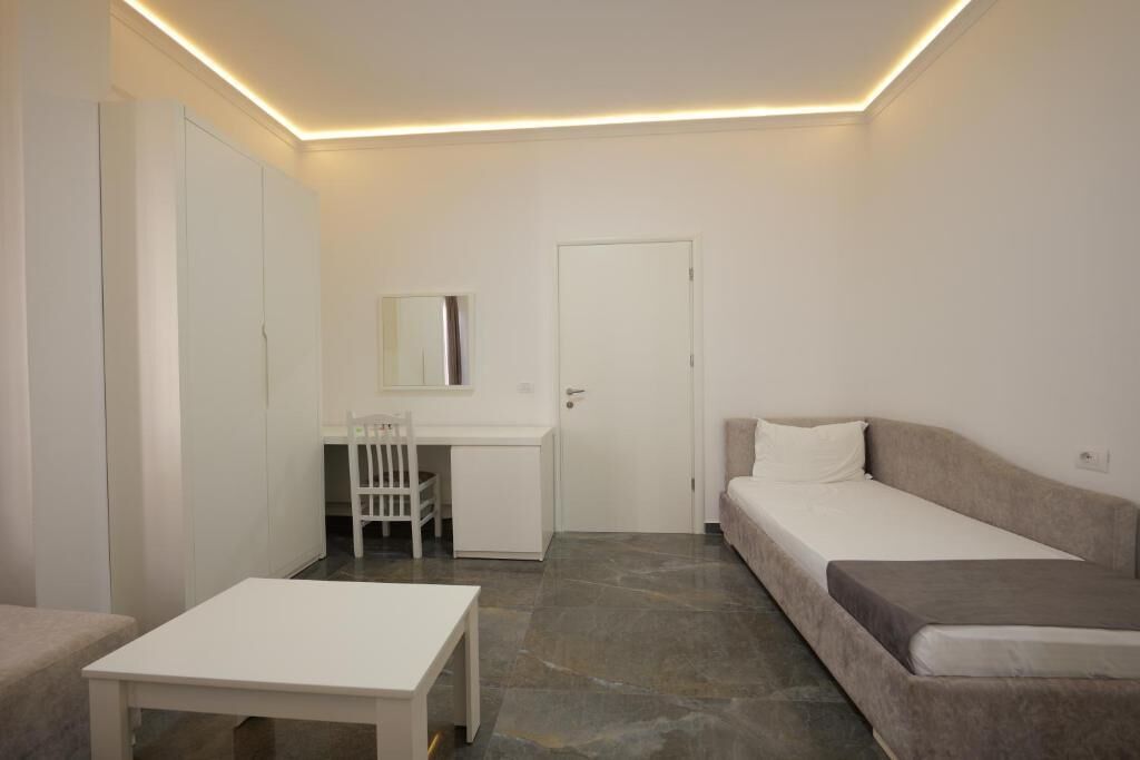 A small, modern room with a bed, a desk, and a chair.