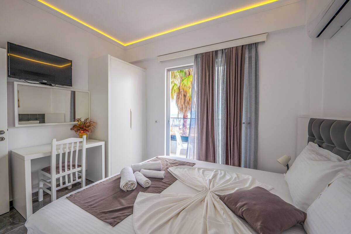 A modern hotel room with a bed, a desk, a chair, and a television.