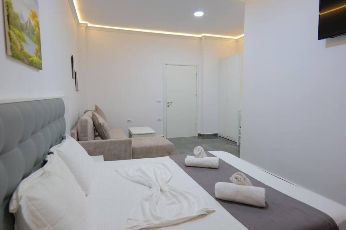 A modern hotel room with a bed, a seating area, and a mirror.