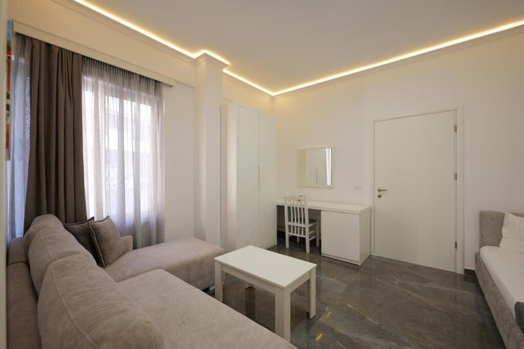 Une chambre d’hôtel moderne et minimaliste, dotée d’un grand canapé, d’une petite table et d’un bureau avec une chaise.