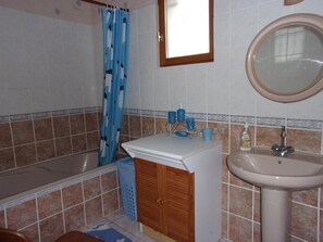 Ein Badezimmer mit einer Badewanne, einem Waschbecken, einem Spiegel und einer Duschvorhang.