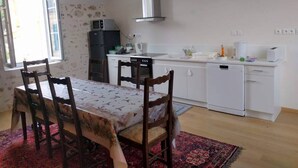 A compact kitchen with a dining area, white cabinets, a microwave, and a dishwasher.