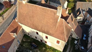 An aerial view of a building with a sloped roof, multiple windows, and a small courtyard with a parked car.
