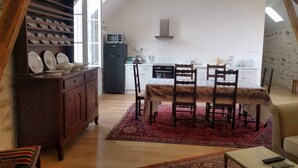 A compact living space with a dining area, kitchen, and a loft bedroom.