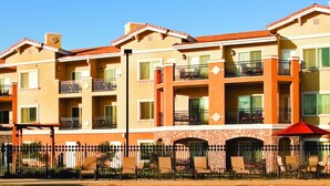 Un hôtel à plusieurs étages doté de balcons, d’un espace extérieur aménagé et d’une façade en briques.