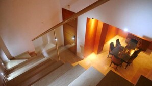 Una scala con ringhiere in vetro conduce a una sala da pranzo con tavolo e sedie.